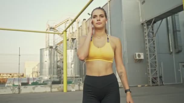 Een Zelfverzekerde Jonge Vrouw Sportkleding Doet Haar Oordoppen Aan Terwijl — Stockvideo