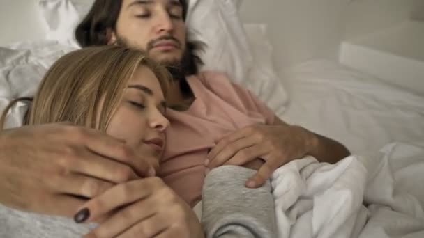 一对年轻貌美的年轻夫妇睡在卧室的床上 — 图库视频影像