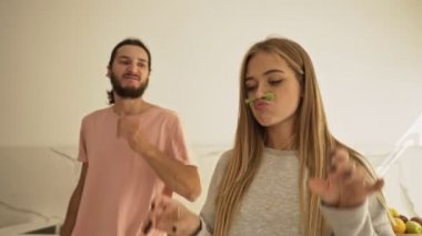 Olumlu, neşeli bir çift mutfakta birlikte salata pişirirken eğleniyor.