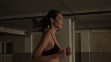 Gün batımında koşan konsantre ve güzel esmer spor kadının yan görüntüsü.