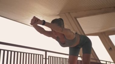 Gülümseyen güzel spor kadını ısınıyor ve dışarı bakıyor.