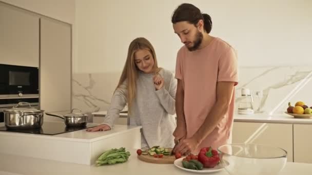 愛の美しいカップルは キッチンに立っている間 一緒に健康的な食事を調理している野菜をスライス — ストック動画