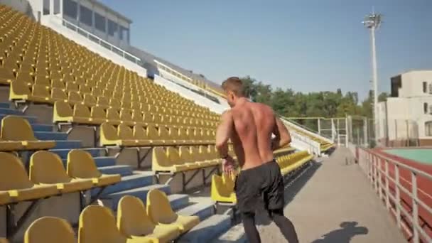 スタジアムの階段を走っている強い若い無気力なスポーツマン — ストック動画