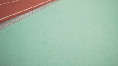 Stadyumdaki maraton için antrenman yaparken kendinden emin genç bir sporcu koşuyor.