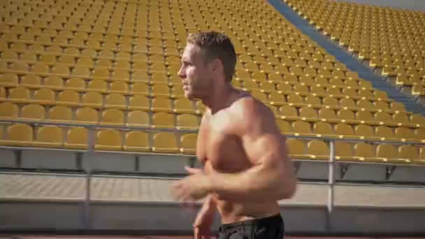 一名全神贯注 肌肉发达 没穿上衣的年轻运动员在体育馆里奔跑 — 图库视频影像