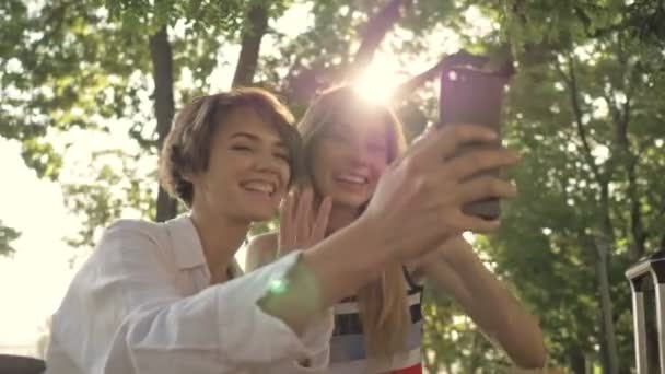 两个快乐的年轻旅游女孩在市区公园里打电话时 正在向摄像机飞吻 — 图库视频影像