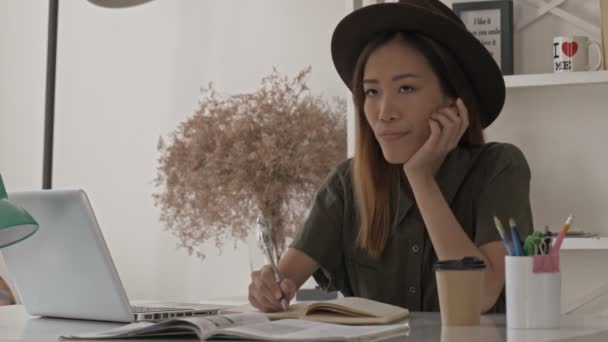 Tankefull Pen Asiatisk Kvinne Med Hatt Som Tenker Noe Skriver – stockvideo