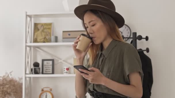Ευτυχισμένη Όμορφη Ασιάτισσα Καπέλο Χρησιμοποιώντας Smartphone Και Πίνοντας Καφέ Στο — Αρχείο Βίντεο