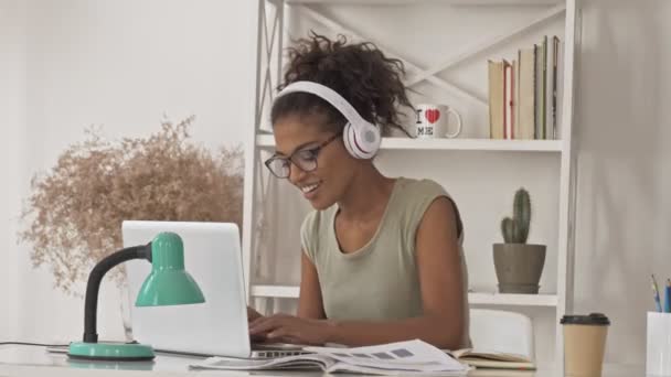 Mujer Africana Bonita Feliz Anteojos Auriculares Usando Computadora Portátil Mientras — Vídeo de stock