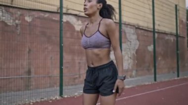Spor giyimli, ciddi bir Afro-Amerikan kadın stadyumda koşuyor.