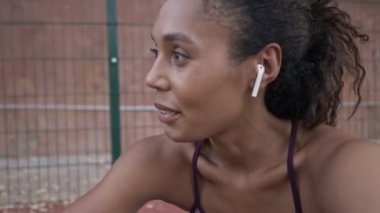 Afro-Amerikalı spor kıyafetleri içinde pozitif bir kadın spor sahasında burpee yapıyor.