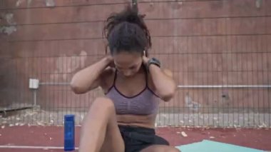 Spor kıyafetleri içinde sakin bir Afrikalı Amerikalı kadın spor sahasındaki yoga minderinde egzersiz yapıyor.