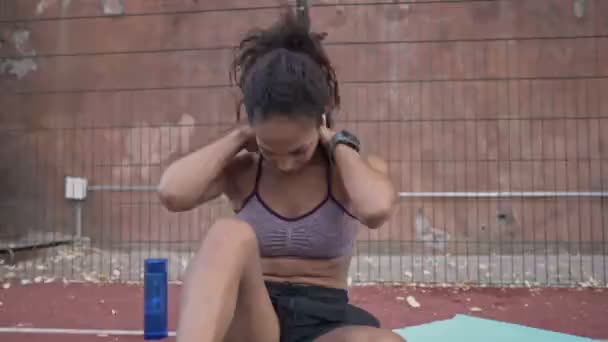 スポーツウェアの穏やかなアフリカ系アメリカ人女性は スポーツグラウンドで屋外ヨガマットで練習をしています — ストック動画