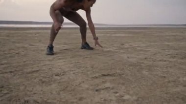 Spor giyimli Afro-Amerikan bir kadının sabahları plajda spor yaparken çekilmiş görüntüsü.