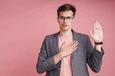 Pembe arka planda tek başına duran ceketli çekici bir adamın portresi, küfür jesti gösteriyor.