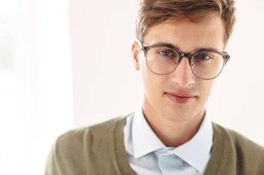 İçerde gözlüklü poz veren konsantre olmuş genç bir öğrencinin resmi..