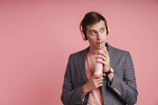 분홍색 고립된 매력적 남성의 헤드폰으로 음악을 병에서 마시고 바라보고 — 스톡 사진