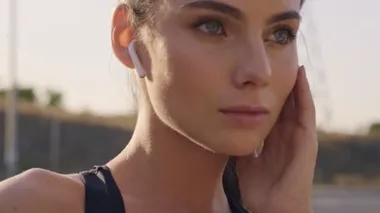 Oldukça genç ve sakin bir fitness kadınının yakından görüntüsü şehir dışında eğitim yaparken kulaklıkla müzik dinliyor.