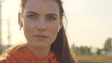 Spor giyim sektöründe yakışıklı bir kadın şehirde antrenman yaparken kablosuz kulaklıklarıyla konuşuyor.