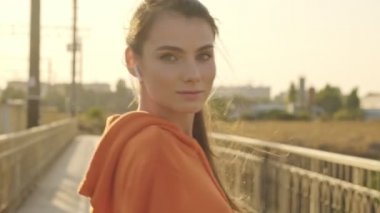 Telsiz kulaklıklı hoş bir genç bayan güneşli bir sabahta köprüde yürüyor.