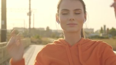 Spor giyimli kendine güvenen genç bir kadın güneşli bir sabahta köprüde yürümekten zevk alıyor.