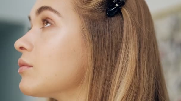 一位专业化妆师的近照正在一家美容院为这位年轻的金发女子化妆 — 图库视频影像