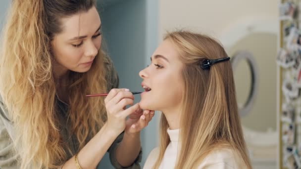 美容室でクライアントに口紅を適用している集中化粧アーティストの側面図 — ストック動画