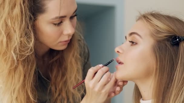 Sidovy Fokuserad Professionell Makeup Artist Applicerar Läppstift Sin Unga Kvinna — Stockvideo