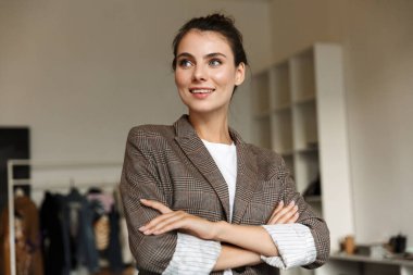 Çekici, kendine güvenen genç bayan tasarımcı ofiste duruyor, kolları bağlı.