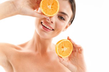 Çekici, gülümseyen, üstsüz, esmer bir kadının portresi. Beyaz arka planda soyutlanmış, dilimlenmiş turuncu renkte duruyor.