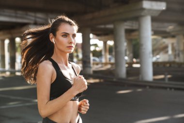 Kulaklıkla müzik dinleyen konsantre olmuş genç bir spor fitness kadınının fotoğrafı..