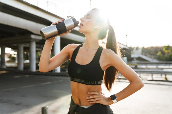 Afbeelding Van Een Mooie Fitnessvrouw Buiten Luistermuziek Met Oortjes Drinkwater — Stockfoto
