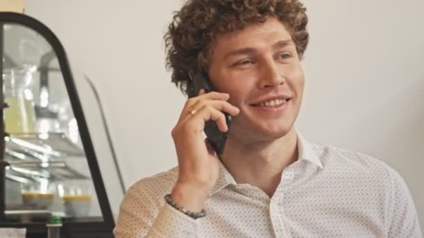Joven Feliz Complacido Está Hablando Por Teléfono Mientras Está Sentado — Vídeos de Stock