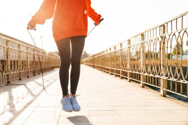 Açık havada spor yapan harika bir kadının kesilmiş fotoğrafı atlama halatıyla egzersiz yapıyor..