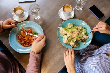Kafe masasında yemek yiyen bir çiftin yakın çekimleri.