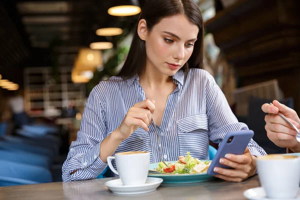 Hermosa Mujer Joven Usando Teléfono Móvil Mientras Almuerza Café Interior — Foto de Stock
