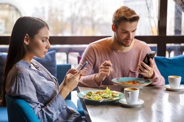 Atractiva Pareja Joven Almorzando Café Interior Comiendo Usando Teléfono Móvil — Foto de Stock