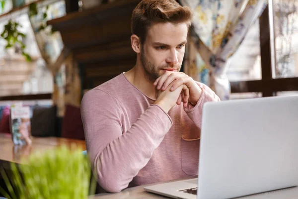 Guapo Joven Pensativo Que Trabaja Ordenador Portátil Mientras Está Sentado —  Fotos de Stock