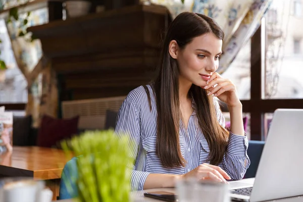 Attraktive Lächelnde Junge Brünette Frau Arbeitet Laptop Während Sie Drinnen — Stockfoto