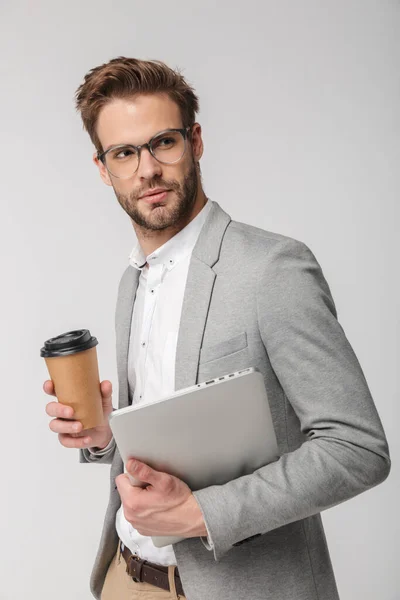 Portret Poważnego Przystojniaka Okularach Pozującego Laptopem Papierowym Kubkiem Białym Tle — Zdjęcie stockowe