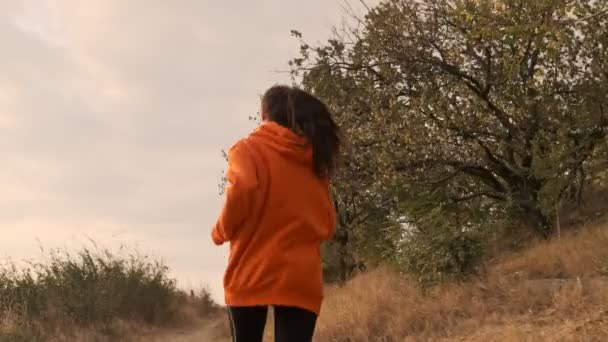 海岸で走り始めたイヤホンの若いかなり運動能力のある女性のバックビュー — ストック動画