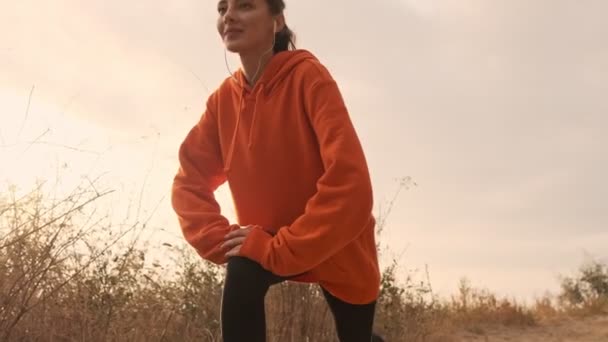Glückliche Hübsche Athletische Frau Mit Kopfhörern Die Sich Mit Beinen — Stockvideo
