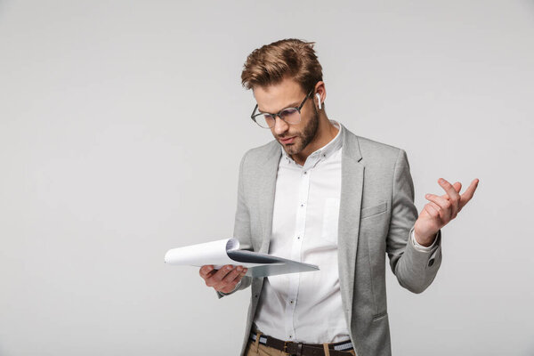 Портрет смущенного красавца в очках в наушниках и с планшетом на белом фоне
