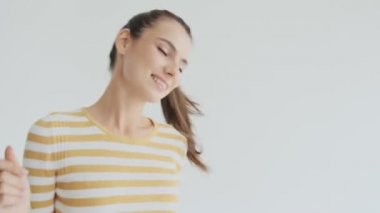 Stüdyoda beyaz arka planda dans eden güzel bir genç kadın var.