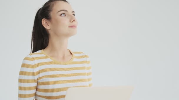 一位年轻貌美的女士一边站在一边 一边在工作室里拿着一台白色背景的笔记本电脑 — 图库视频影像