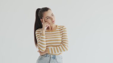 Ciddi bir genç kadın stüdyoda beyaz bir geçmişle ilgili bir şeyler düşünüyor.