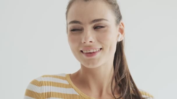 Uma Jovem Sorrindo Sedutora Com Fones Ouvido Sem Fio Está — Vídeo de Stock