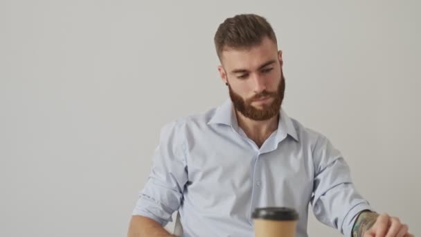 白いオフィスで働いている間に シャツを着て疲れた若い男が鼻の橋に触れている — ストック動画