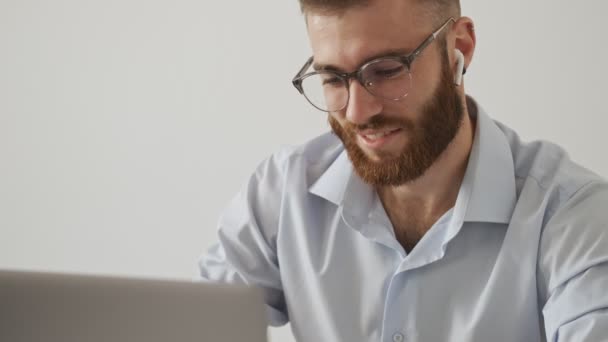 Usměvavý Vousatý Mladík Brýlích Zapíná Airpody Zatímco Používá Notebook Přes — Stock video