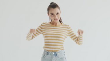 Yakışıklı genç bir kadın stüdyodaki beyaz arkaplanı işaret ediyor.